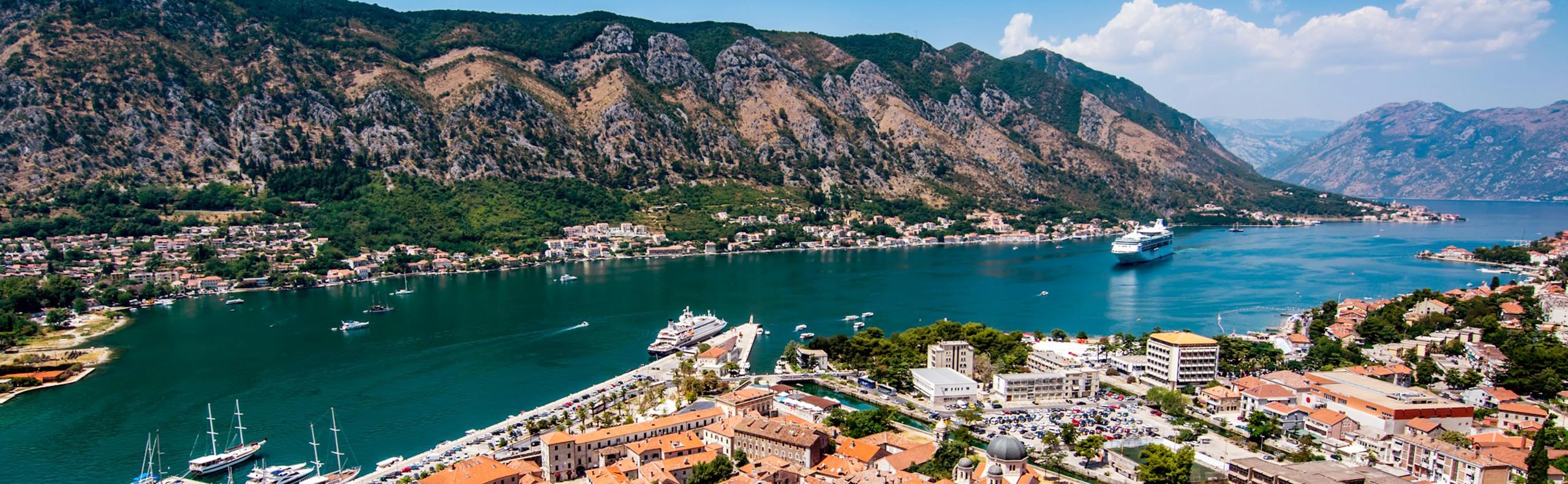 Kotor, Montenegro, photo of mountains and a town surrounding a small inlet with cruise ships, 