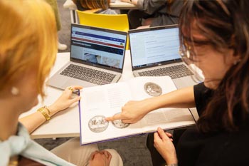 Two people looking at and pointing at a textbook